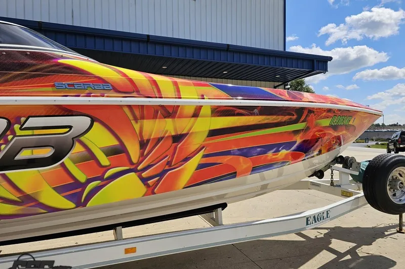 Slide: The Image of Colorful 1995 Wellcraft 29 Scarab boat with vibrant graphics on a trailer. - 6