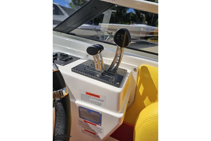 Slide: The Image of 1995 Wellcraft 29 Scarab boat controls with dual throttle levers and warning labels. - 64