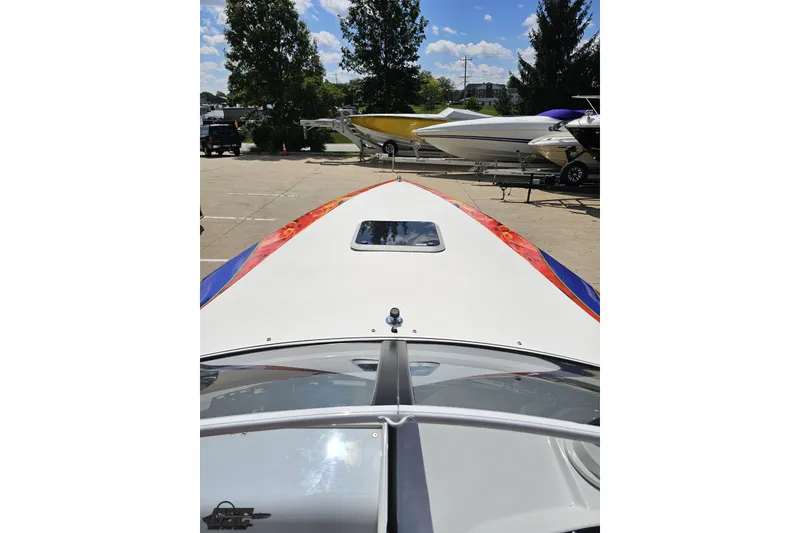 Slide: The Image of 1995 Wellcraft 29 Scarab boat with colorful design, docked under a sunny sky. - 66