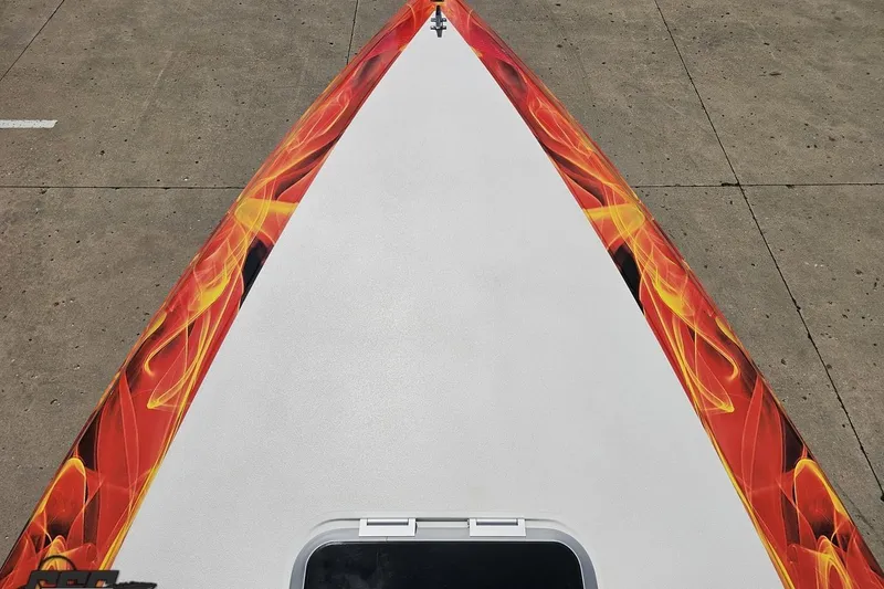 Slide: The Image of Bow of 1995 Wellcraft 29 Scarab with vibrant flame graphics on concrete surface. - 68