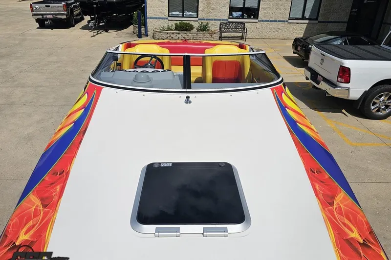 Slide: The Image of 1995 Wellcraft 29 Scarab boat with vibrant flame graphics, parked outdoors. - 70