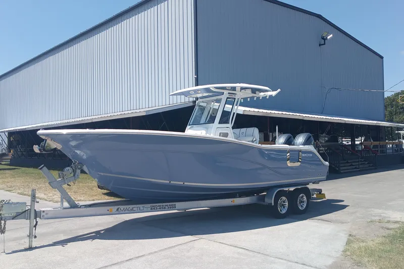 The Image of 2025 Seafox 268c Commander boat on trailer, parked near a large warehouse. - 0