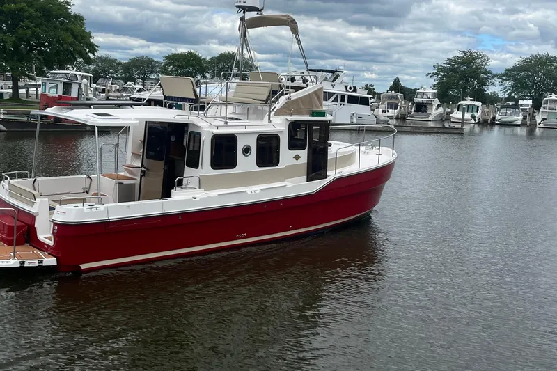 Slide: The Image of 2026 Ranger Tugs R-31 Command Bridge Luxury Edition in marina, red hull, calm waters. - 3