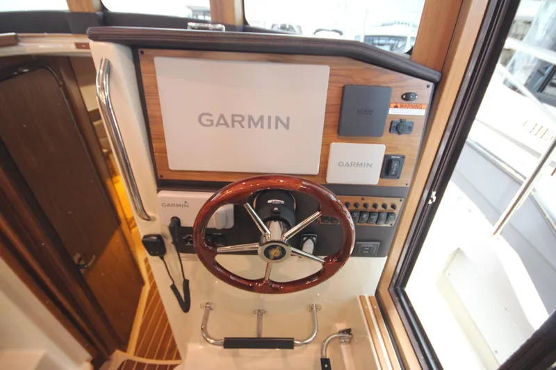 Slide: The Image of 2026 Ranger Tugs R-31 Command Bridge helm with Garmin navigation system and wooden steering wheel. - 59