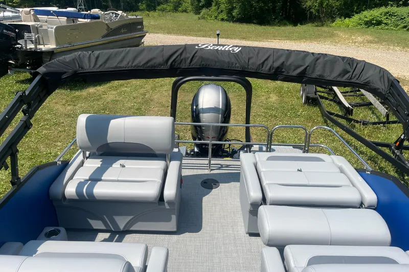 Slide: The Image of 2025 Bentley Pontoons Legacy QSB with sleek seating and canopy, set on grassy terrain. - 14
