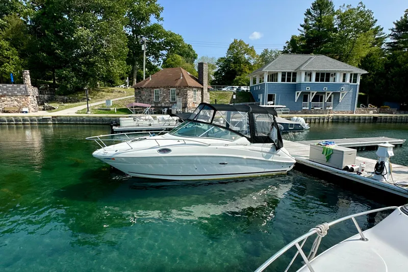 Slide: The Image of 2012 Sea Ray 240 Sundancer docked in clear water near rustic buildings. - 0