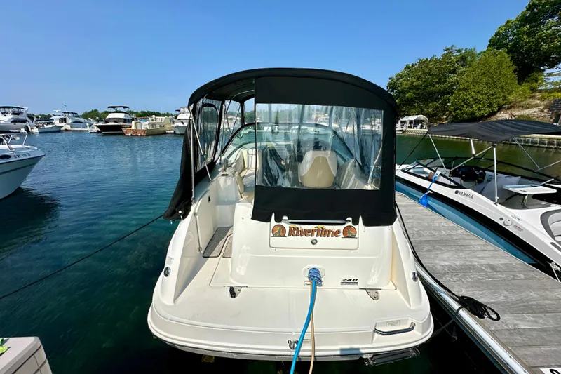Slide: The Image of 2012 Sea Ray 240 Sundancer docked at marina, rear view with canopy. - 1