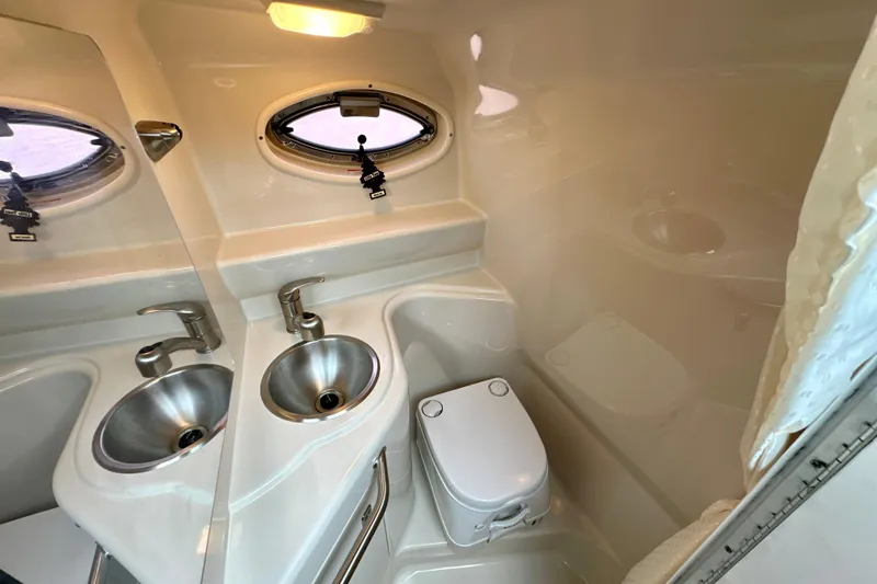 Slide: The Image of 2012 Sea Ray 240 Sundancer bathroom with stainless steel sink and compact toilet. - 10