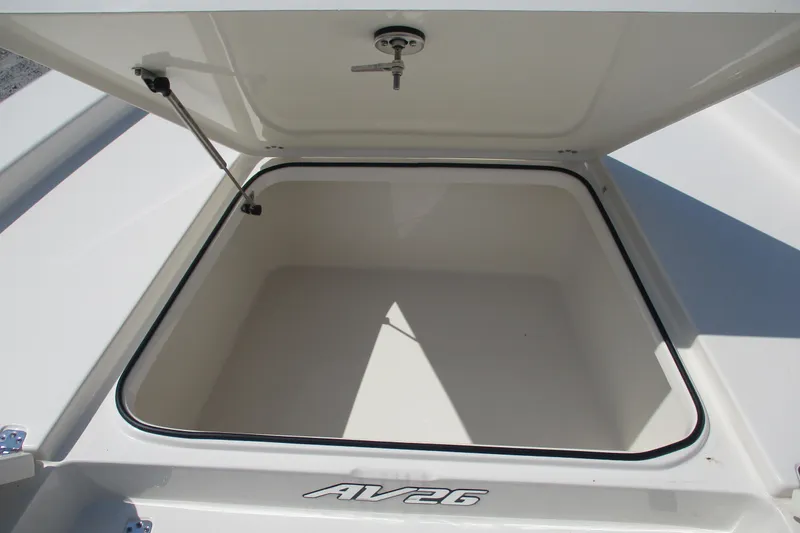 Slide: The Image of Open storage compartment of 2026 Avenger AV26 boat, featuring secure latch and spacious interior. - 13