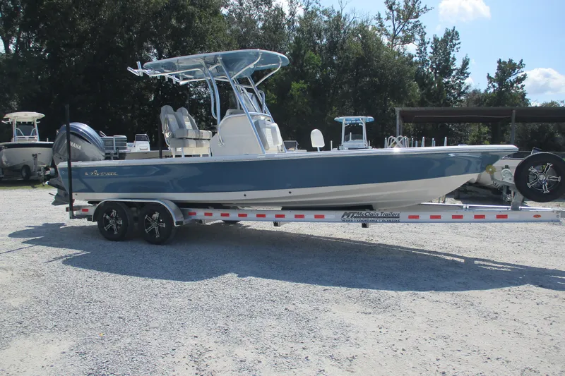 Slide: The Image of 2026 Avenger AV26 boat on trailer, parked outdoors, with trees in the background. - 6