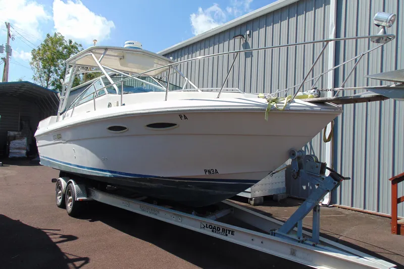 The Image of 1988 Sea Ray 270 Amberjack boat on trailer, parked outdoors near metal building. - 1