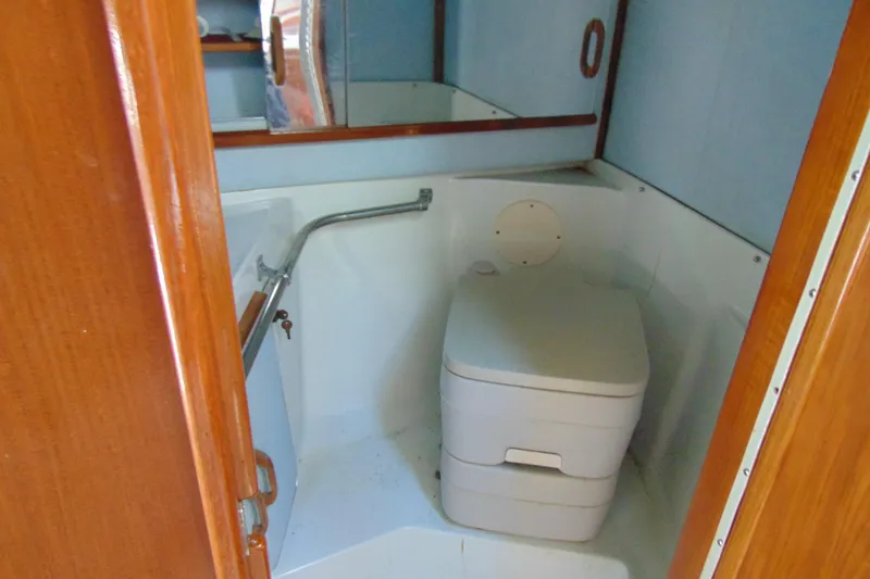 Slide: The Image of 1988 Sea Ray 270 Amberjack boat bathroom with compact toilet and wooden accents. - 13