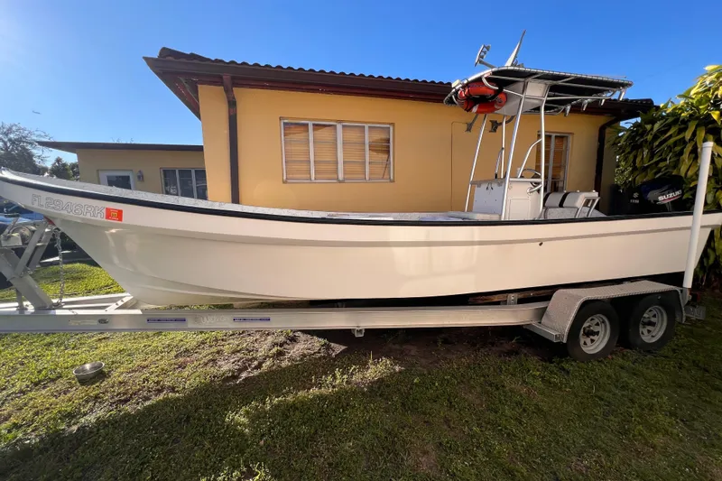 Slide: The Image of 2017 Panga Minsa boat on trailer with Suzuki outboard motor, parked beside a yellow building. - 6