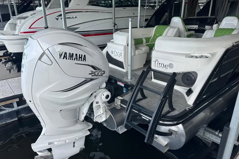 Slide: The Image of 2022 Bennington QX 25 Quad Bench interior with green and white seating under canopy. - 10