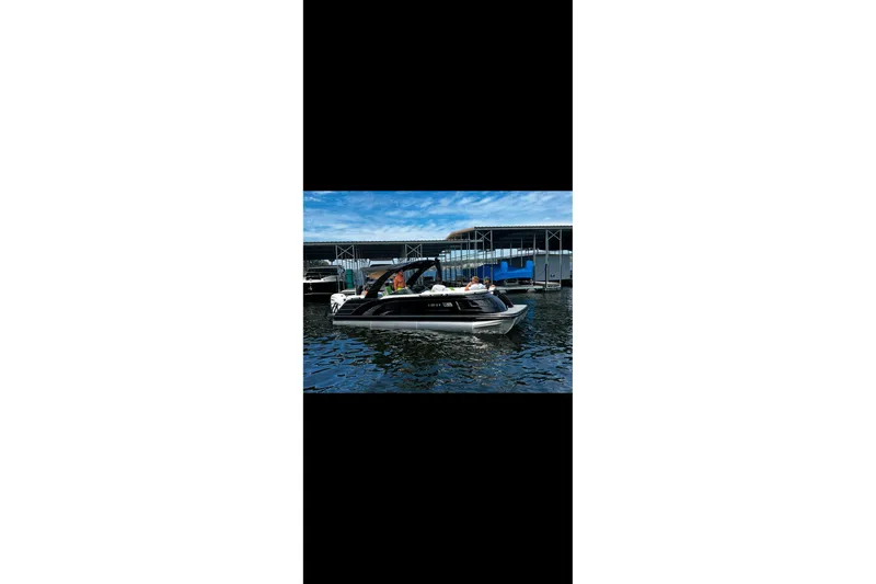 Slide: The Image of 2022 Bennington QX 25 Quad Bench with green and white seating in a marina. - 3