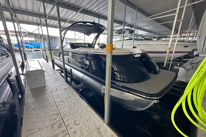 Slide: The Image of 2022 Bennington QX 25 Quad Bench interior with green and white seating, docked by the water. - 8