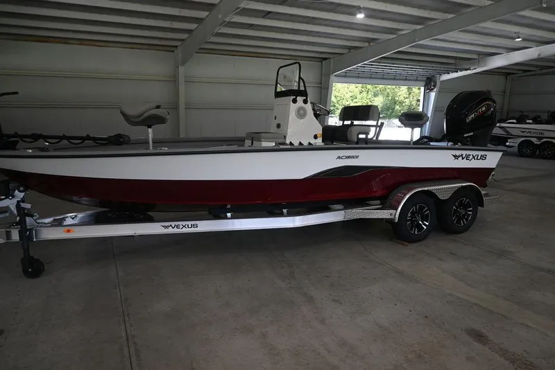 The Image of 2026 Vexus ACX 2210 boat in a garage, featuring a sleek design and dual-axle trailer. - 1