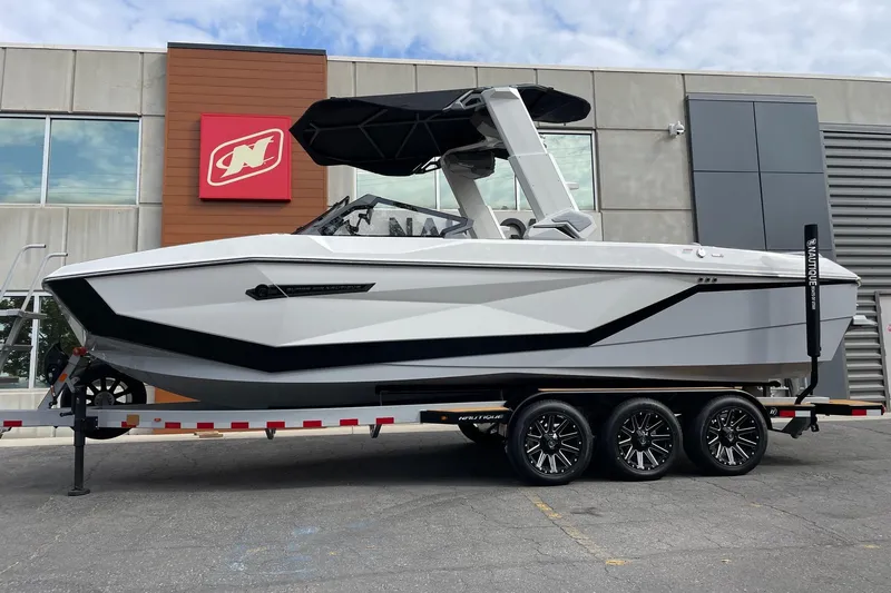The Image of 2026 Nautique Super Air Nautique G25 boat on trailer outside dealership. - 1