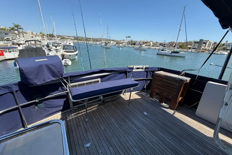 Slide: The Image of 1991 Kong & Halvorsen Island Gypsy yacht deck with marina view, featuring blue seating and wooden flooring. - 50