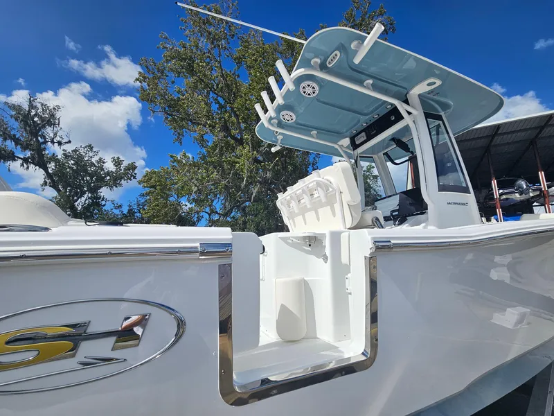 Slide: The Image of 2025 Sea Hunt Ultra 239 SE boat, white exterior, blue sky background, trees visible. - 11