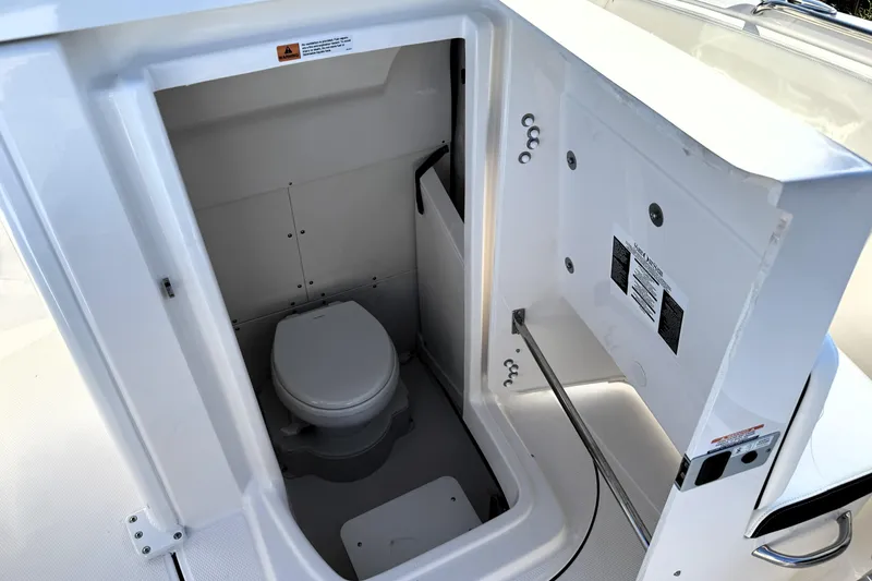 Slide: The Image of 2025 Robalo R270 Center Console boat interior with compact marine toilet. - 16