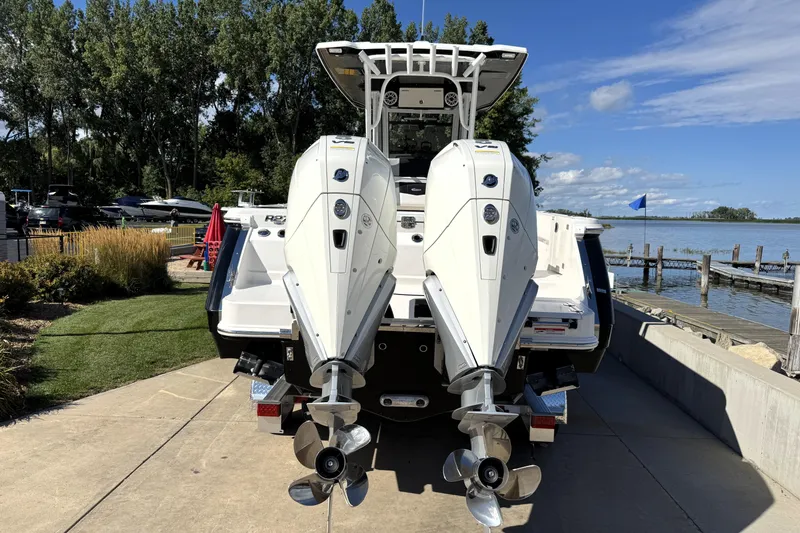 Slide: The Image of 2025 Robalo R270 Center Console boat with dual outboard engines at a lakeside dock. - 2