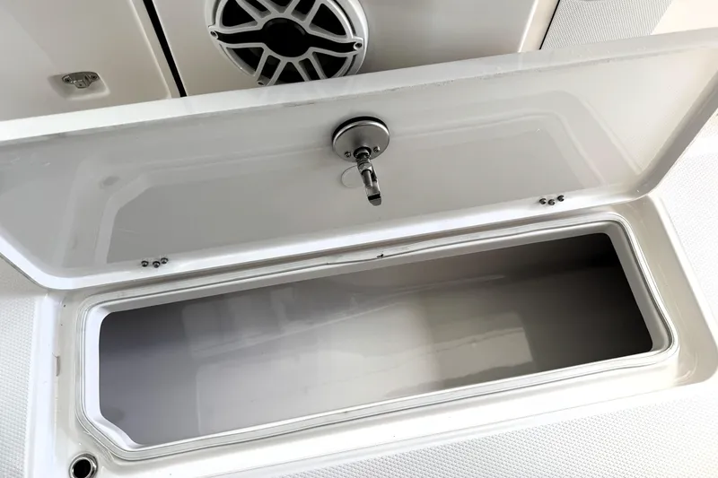 Slide: The Image of 2025 Robalo R270 Center Console storage compartment with open lid and speaker detail. - 26