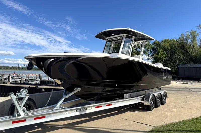 Slide: The Image of 2025 Robalo R270 Center Console boat on trailer by the dock under clear blue sky. - 5
