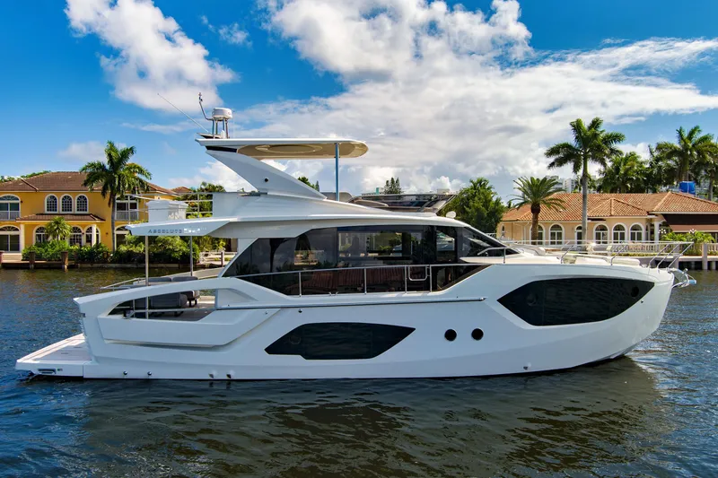 Slide: The Image of 2025 Absolute 52 FLY yacht on a sunny waterfront with palm trees and luxury homes. - 1