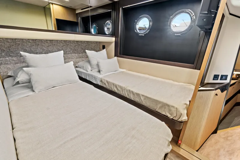 Slide: The Image of Luxurious cabin interior of 2025 Absolute 52 FLY yacht with twin beds and porthole windows. - 57