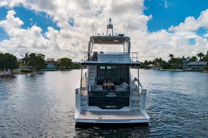 Slide: The Image of 2025 Absolute 52 FLY yacht on a serene waterway under a partly cloudy sky. - 6