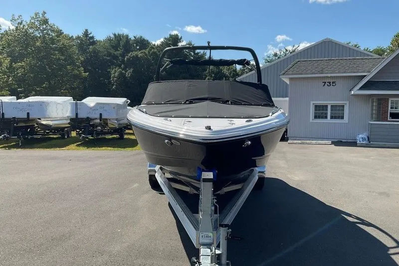 Slide: The Image of 2026 Chaparral 23 SSi OB boat on trailer, parked outside a building. - 11