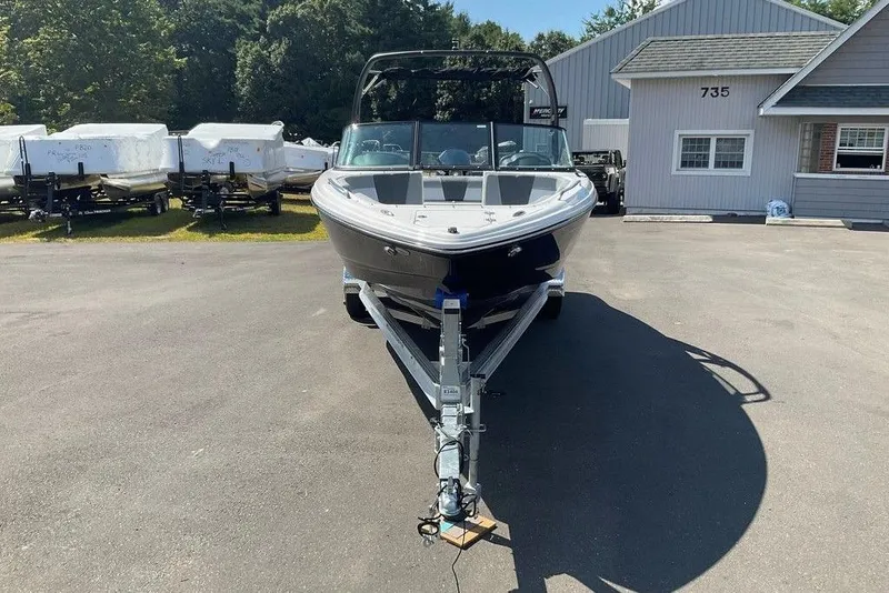 Slide: The Image of 2026 Chaparral 23 SSi OB boat on trailer, parked outdoors near building. - 2