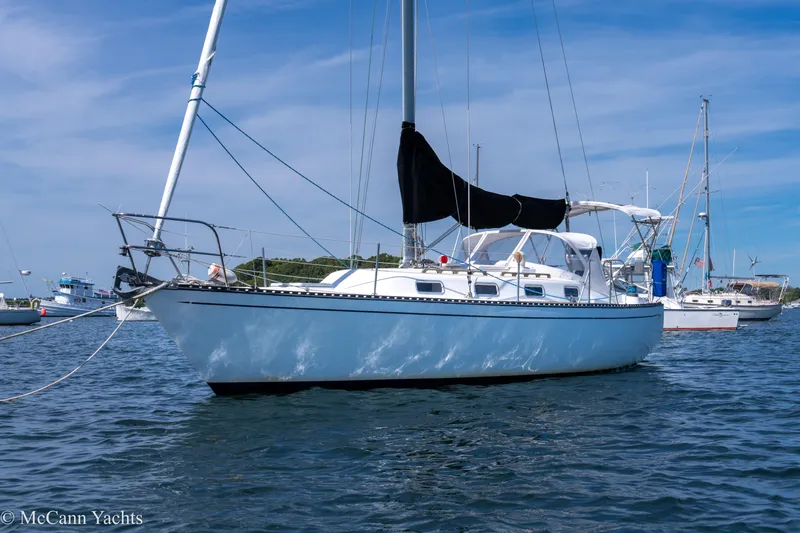 Slide: The Image of 1985 Tartan 34-2 sailboat anchored on calm water under a clear blue sky. - 0