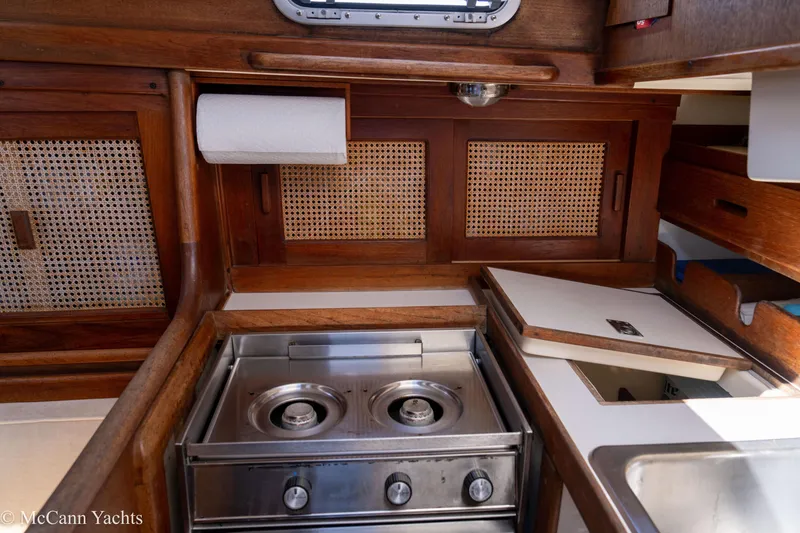 Slide: The Image of 1985 Tartan 34-2 yacht galley with stove, wooden cabinetry, and sink. - 11