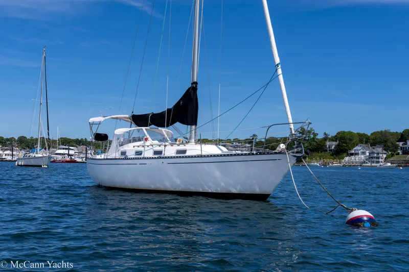 Slide: The Image of 1985 Tartan 34-2 sailboat anchored in a scenic harbor under a clear blue sky. - 2