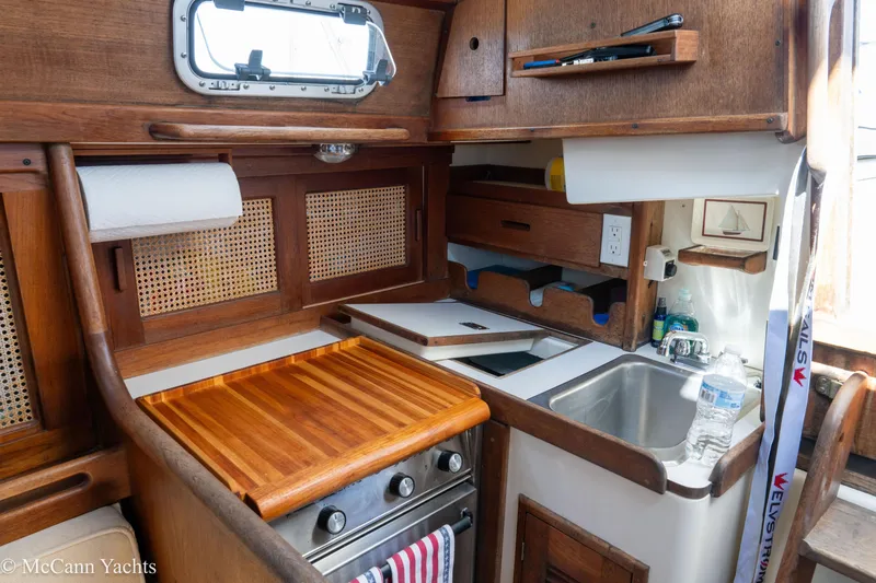 Slide: The Image of 1985 Tartan 34-2 yacht kitchen with wooden cabinetry, stove, and sink. - 22