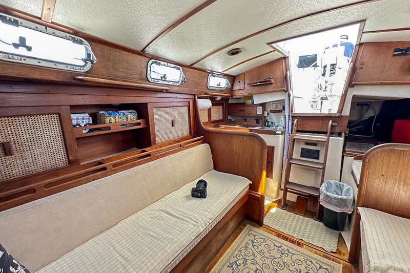 Slide: The Image of Interior of 1985 Tartan 34-2 sailboat with wooden furnishings and cozy seating area. - 34