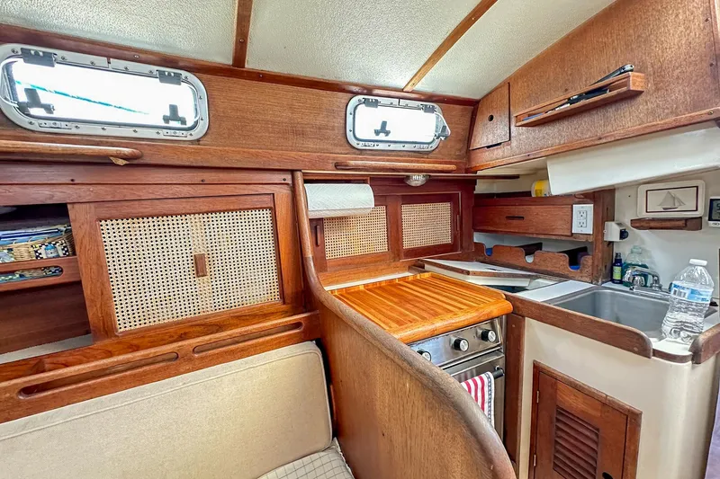 Slide: The Image of Cozy 1985 Tartan 34-2 sailboat interior with wooden cabinetry and compact kitchen area. - 37