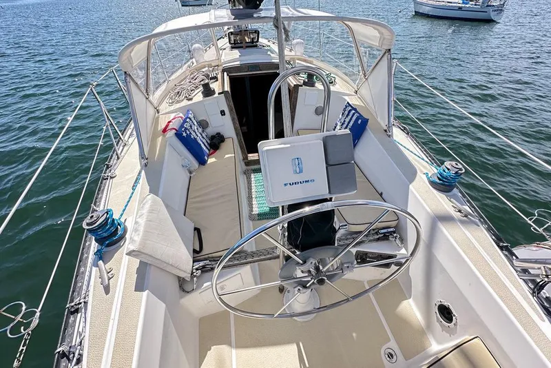 Slide: The Image of 1985 Tartan 34-2 sailboat cockpit with steering wheel, cushions, and navigation equipment on water. - 4