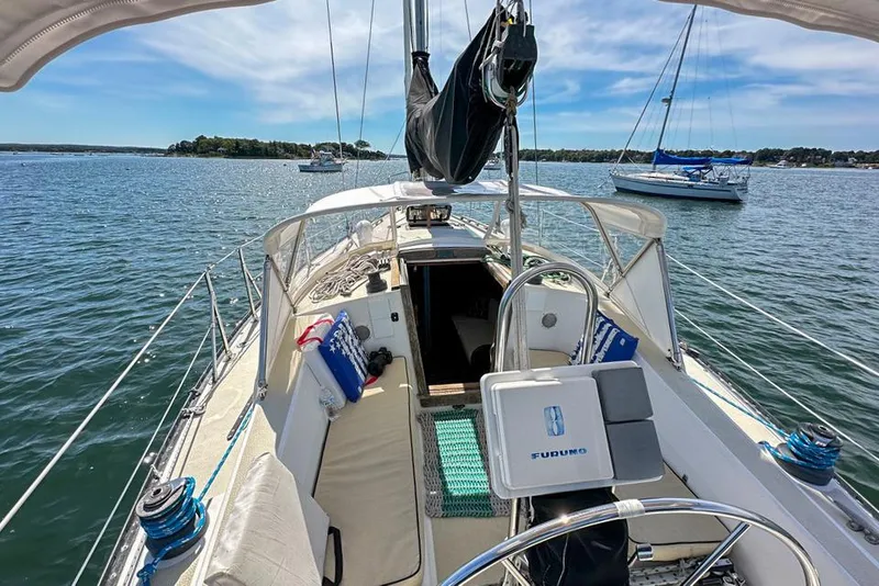 Slide: The Image of 1985 Tartan 34-2 sailboat on calm water, featuring a spacious deck and clear skies. - 5