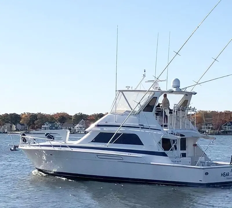 Slide: The Image of 1995 Bertram 50 Convertible yacht cruising on a calm lake with autumn trees in the background. - 1