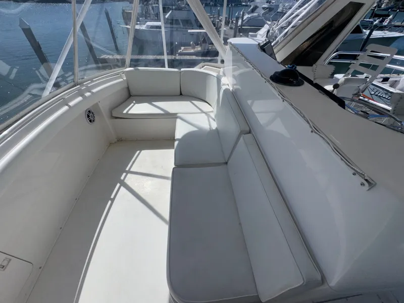 Slide: The Image of 1995 Bertram 50 Convertible yacht interior with white seating and marina view. - 13