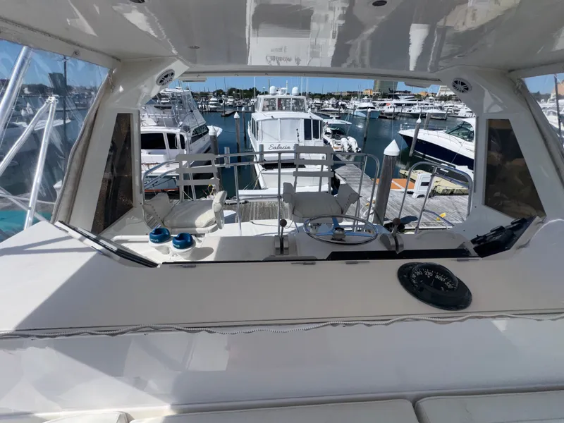 Slide: The Image of Bertram 50 Convertible 1995 yacht helm with marina view, featuring steering wheel and controls. - 15