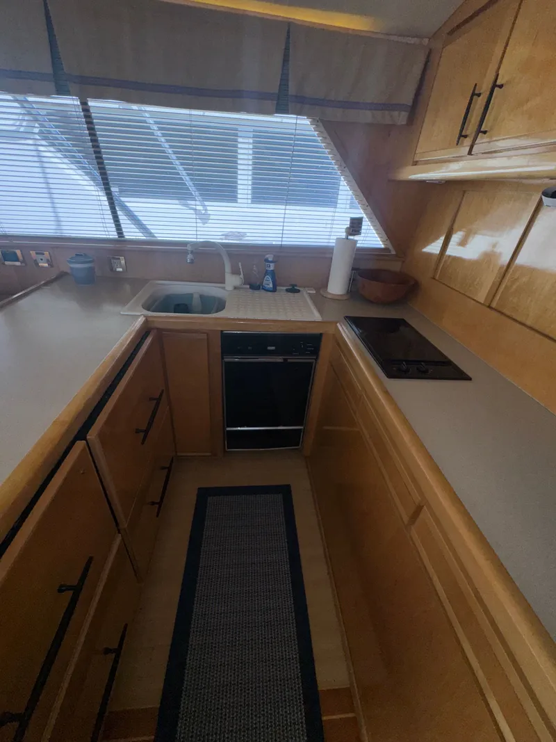 Slide: The Image of Compact kitchen in a 1995 Bertram 50 Convertible yacht with wooden cabinets and modern appliances. - 25
