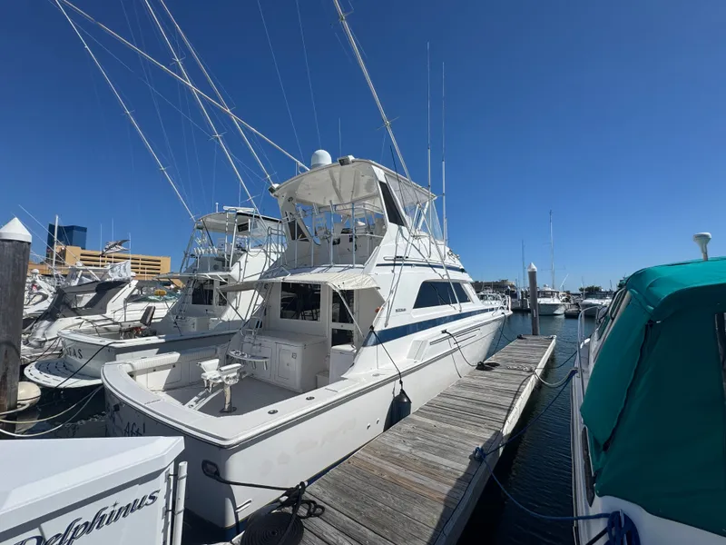 Slide: The Image of 1995 Bertram 50 Convertible yacht docked at marina under clear blue sky. - 4