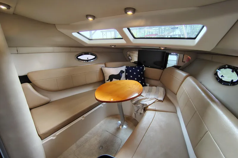 Slide: The Image of 2008 Regal 2565 Window Express cabin interior with beige seating and wooden table. - 2