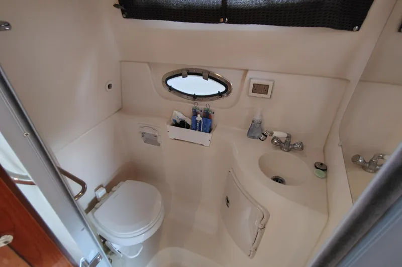 Slide: The Image of 2008 Regal 2565 Window Express boat bathroom with toilet, sink, and porthole window. - 24