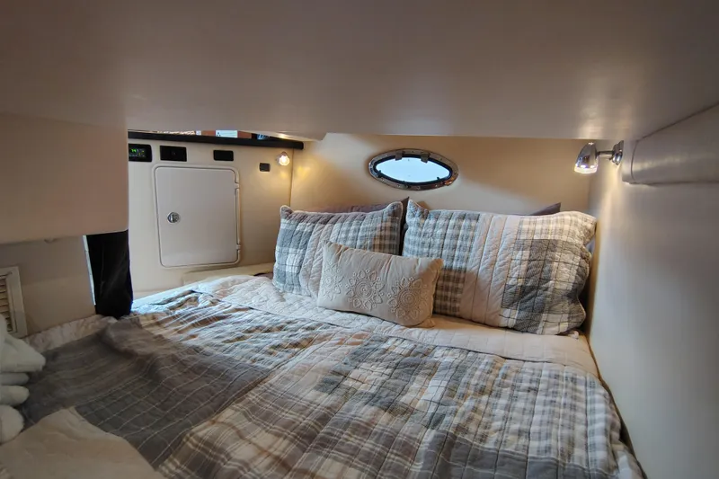 Slide: The Image of Cozy cabin interior of 2008 Regal 2565 Window Express with plaid bedding and porthole window. - 27