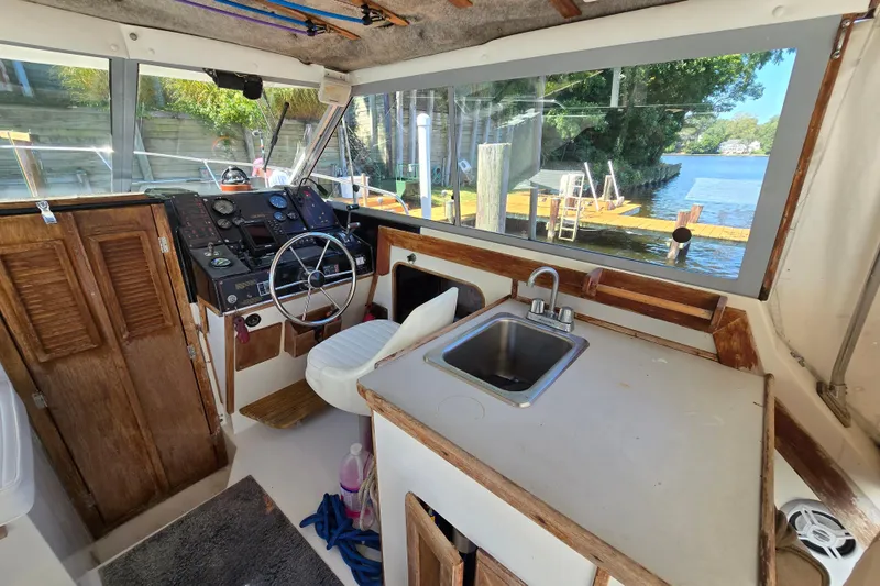 Slide: The Image of 1984 Bayliner 2802 Trophy boat interior with steering wheel, sink, and wooden cabinetry. - 31